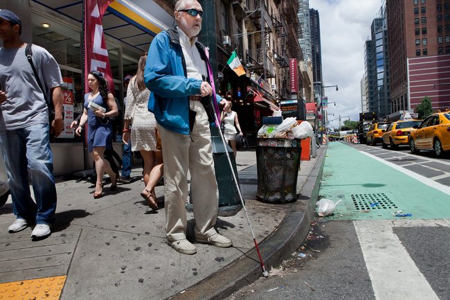 Young blind person with long cane walking in a city Stock Photo by