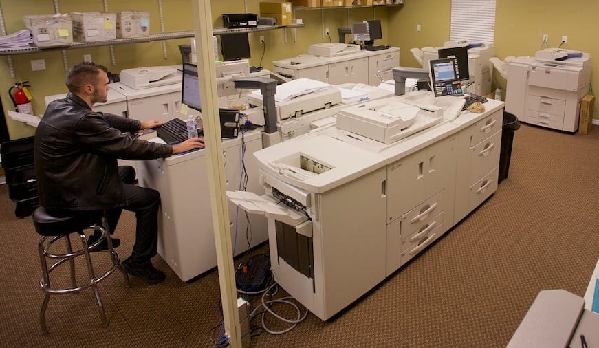 A Braille Works employee operating printers in the Large Print department