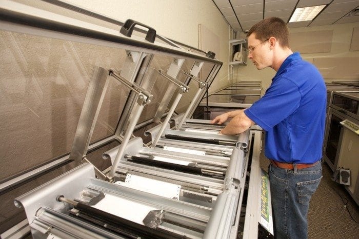 Image of a Braille Works employee loading paper into a braille embosser.