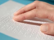 Close-up image of a person reading Braille with one hand.