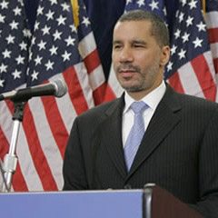 David Paterson standing behind a podium and microphone