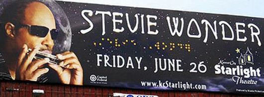 Billboard promoting a Stevie Wonder concert with braille characters spelling his name