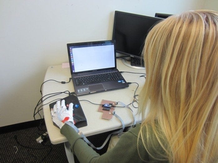 Image showing a young woman sitting in front of her laptop wearing a computing braille glove.