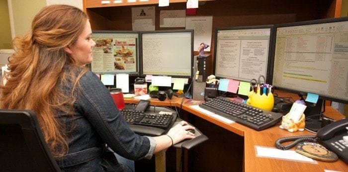 Image showing a Braille Works employee at her desk converting documents to braille and large print formats.