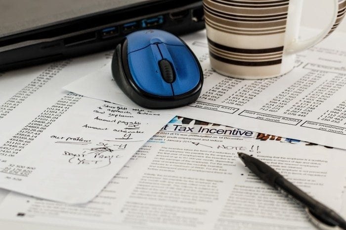 Computer mouse, mug, and pen on top of financial papers