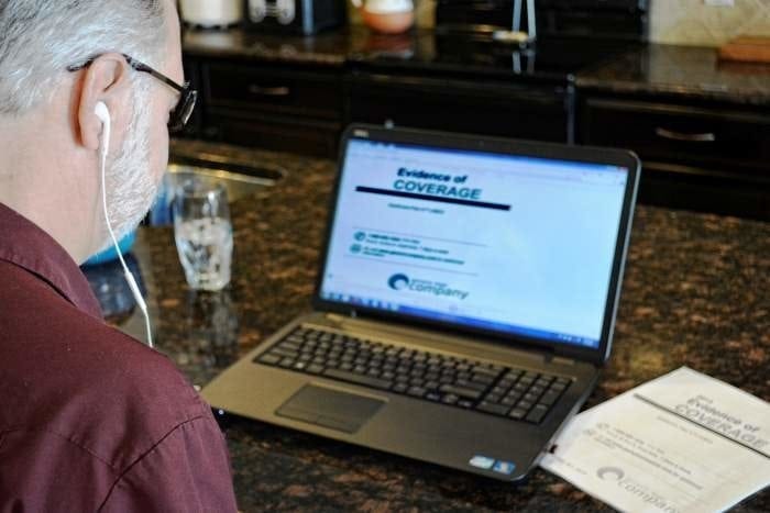 A man sitting in front of his laptop computer listening to a 508 Compliant accessible PDF document with Screen Reading software.