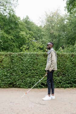 man with white cane and dark glasses walking outside