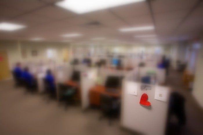 A blurry image showing several Braille Works employees working at their desks. The blurry effect is being used to demonstrate a visual impairment.