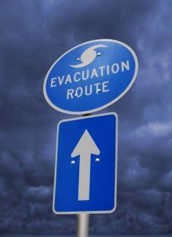 Blue "evacuation route" street sign with an arrow underneath pointing which direction to go.