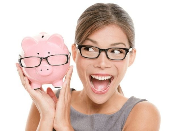 Woman in glasses smiling and holding a pink piggy-bank that also has glasses on.