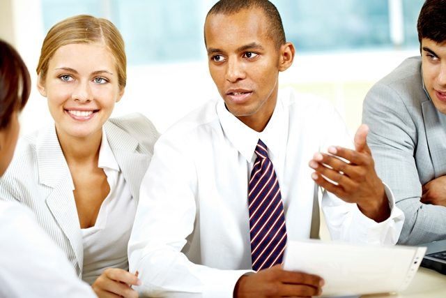 Several business people sitting around a table and talking.