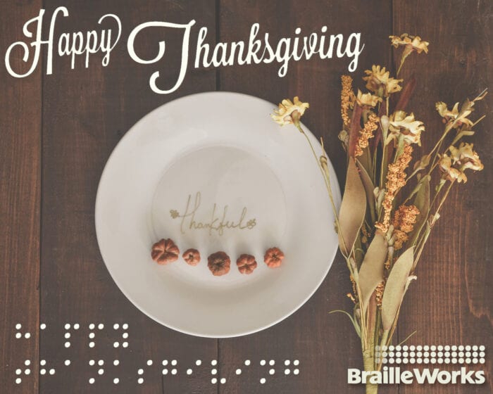 Dried flowers next to a plate with the word "thankful" on it and the words "Happy Thanksgiving" in print and braille with the Braille Works logo