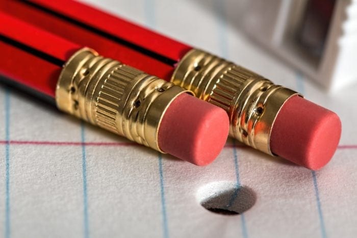 Close up view of two pencil erasers on top of notebook paper.