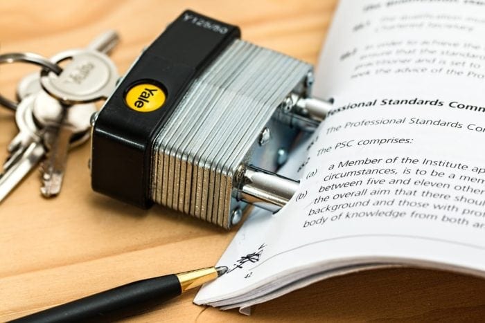 Padlock holding a small stack of paper together.