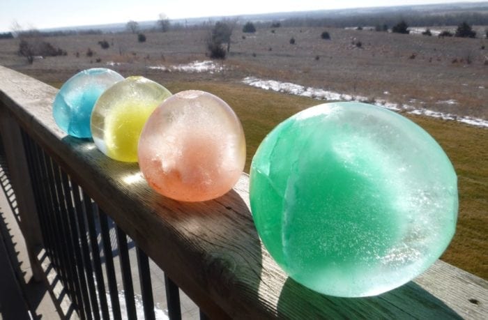 Four winter marbles sitting on a patio railing.