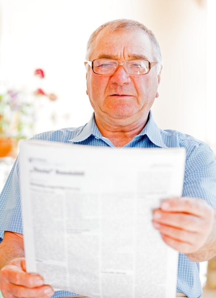 A man struggling to read a print document.