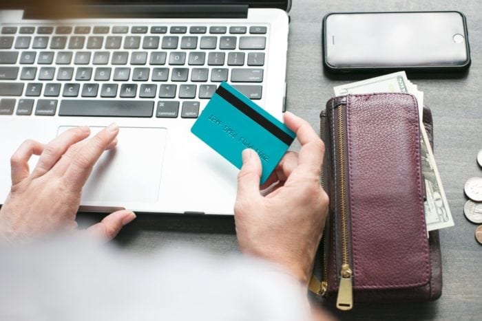 Woman sitting at a desk using her laptop and debit card.