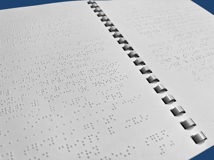 Close up of an open braille document with GBC comb binding