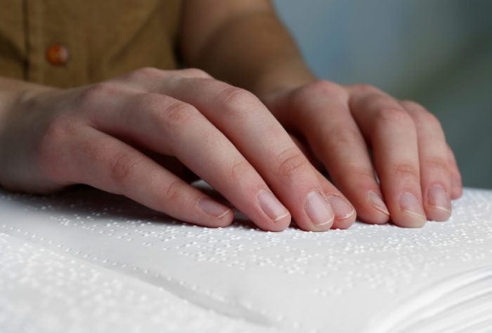 Close up view of someone reading a braille book.