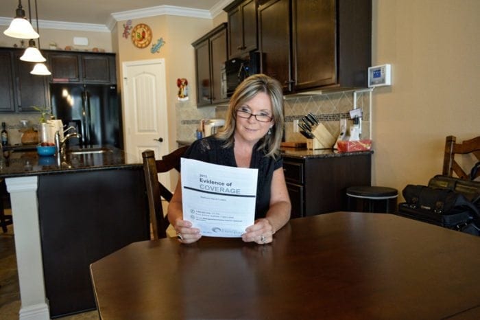 Woman sitting at her kitchen table reading a large print document.