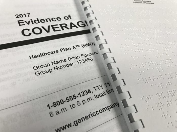 close up of a Braille and large print Evidence of Coverage documents.