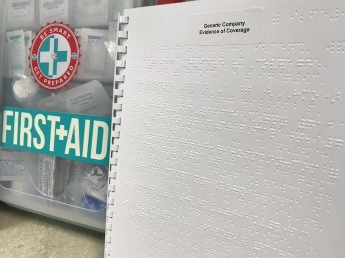 Braille Evidence of Coverage document and a first aid kit