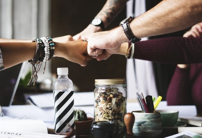 Four member business team doing a fist-bump.