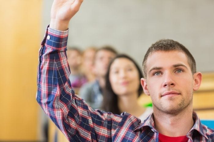 Student raising his hand in a classroom