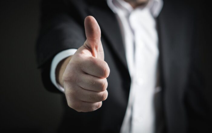 man in a suit giving a thumbs up sign