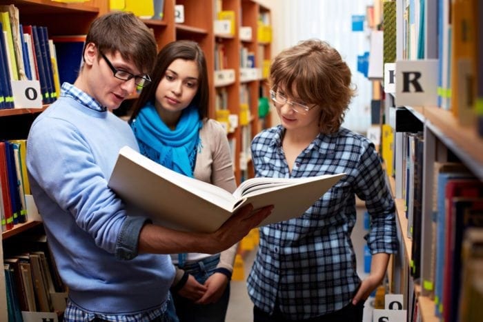 college students looking at a library textbook together