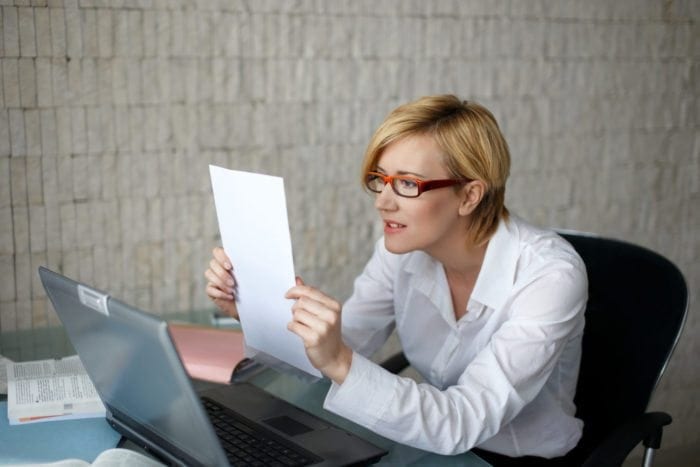 business woman squiting to read a document that doesnt meet compliance.