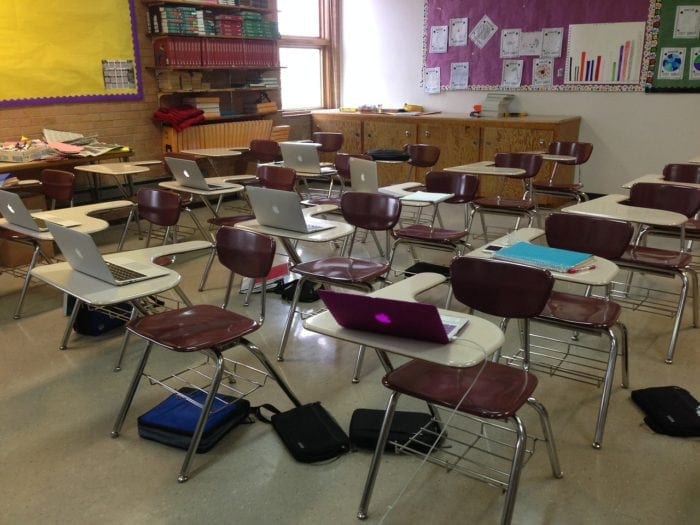 classroom desks with laptops atop desks
