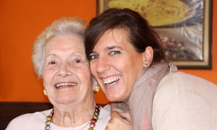 daughter and elderly mother sitting together with big smiles on face