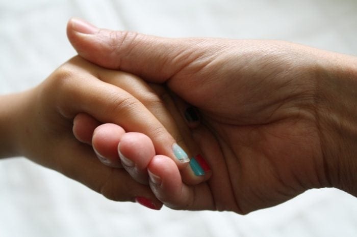 child's hand with nail polish holding an adults hand
