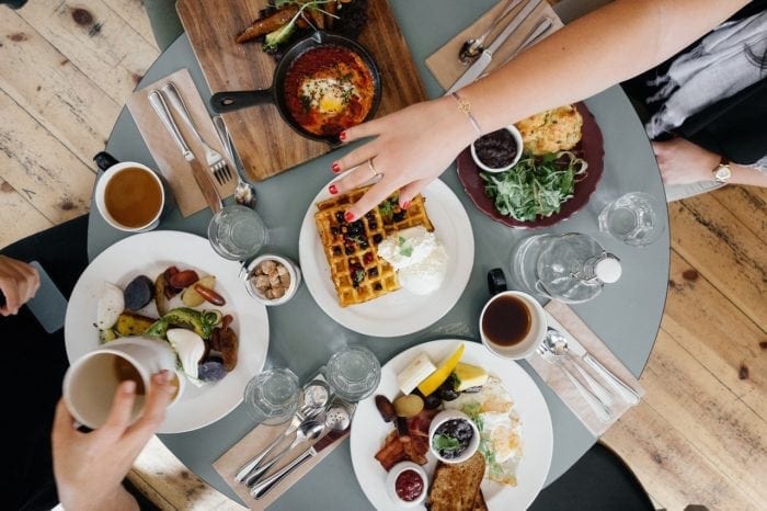 Overhead view of a breakfast meal, one hand reaching across the table