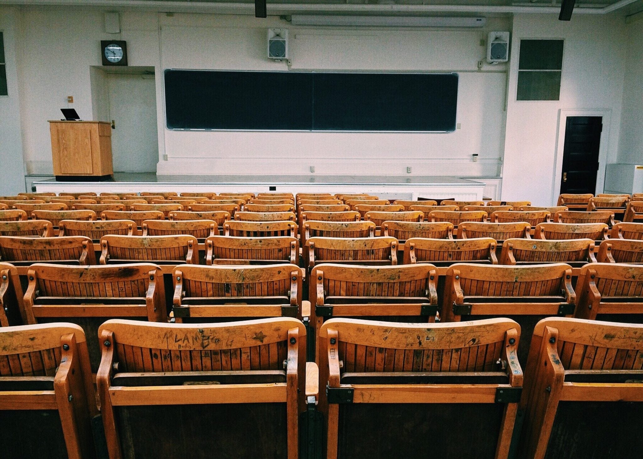 Empty auditorium with wood chairs, blackboard and podium