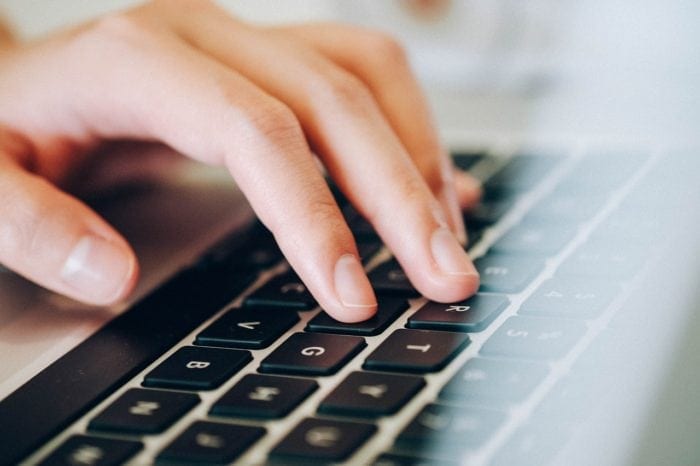 a close up of a hand typing on a laptop