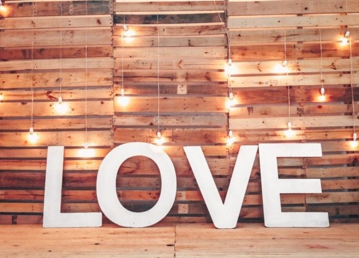 Large letters spelling "love" surrounded by wooden pallets and light bulbs