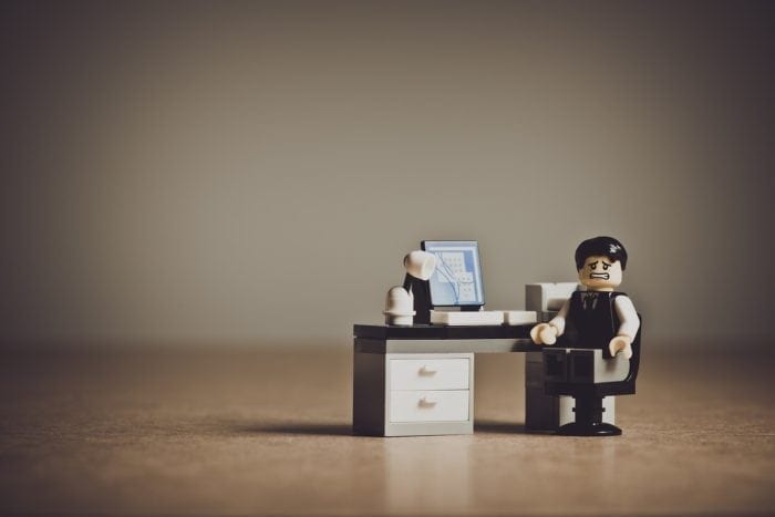Confused lego man looking sitting at an office desk