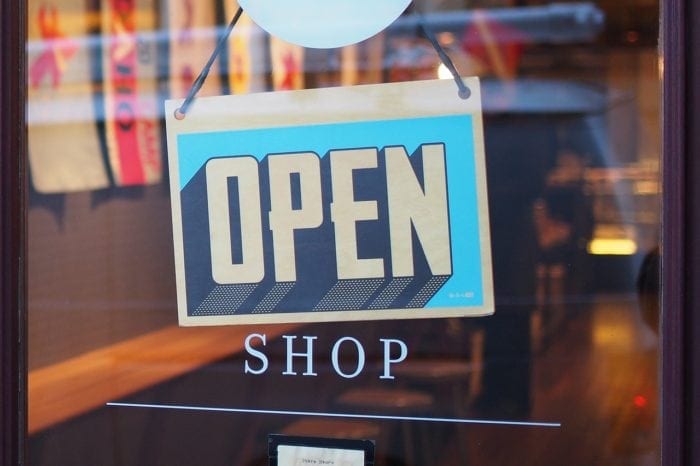 an open shop sign in front of a clear door entrance