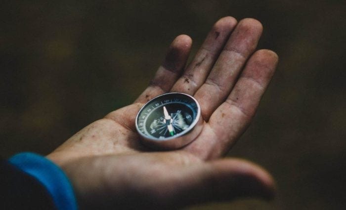 Dirty hand holding a compass