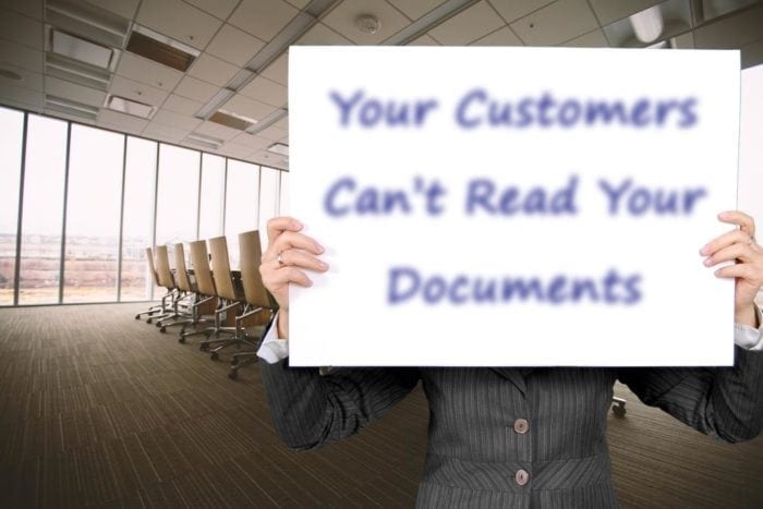 Conference room with someone standing at the front with a large card in front of their face with blurry text that reads, "Your Customers Can't Read Your Documents"