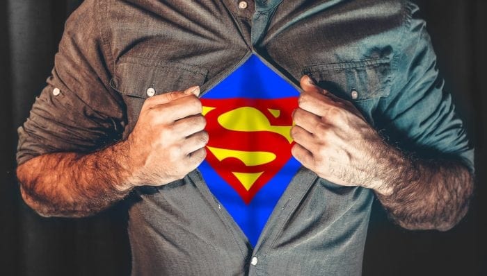 Man's torso with shirt unbuttoned to reveal the Superman logo 