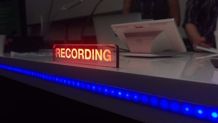 A recording booth in session with the "recording" sign illuminated