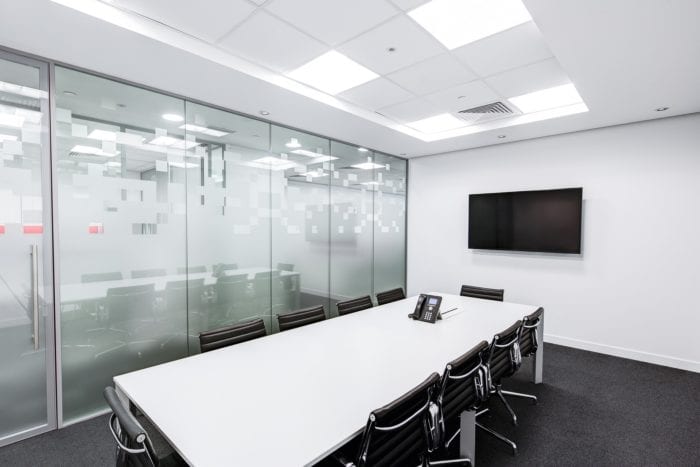 Empty conference room with chairs around a long table, phone on the table and tv mounted on the wall