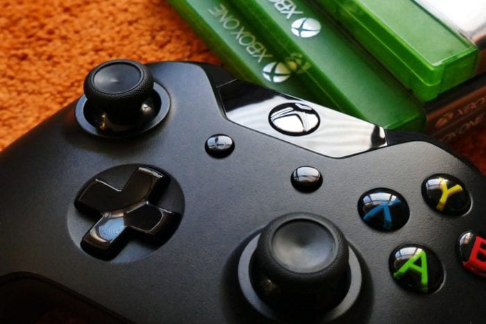 Close-up of an Xbox controller with Xbox ONE game cases in the background.