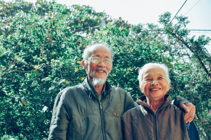 Smiling elderly man with his arm around a smiling elderly woman