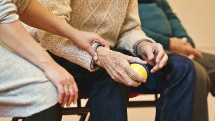 Adult child hands gently holding their aging parent's wrist