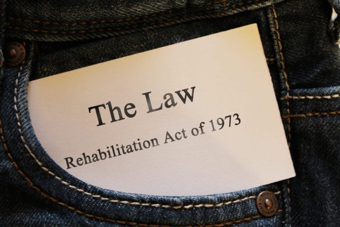 Jean pocket with a card sticking out that says, "The Law Rehabilitation Act of 1973"