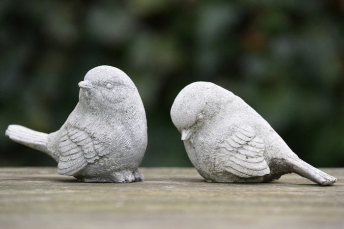 Exclusion of one stone bird that's looking down by another stone bird that's looking away